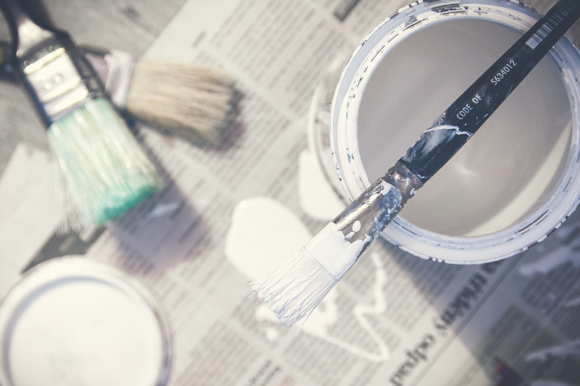 paint brushes and paint on newspaper. 